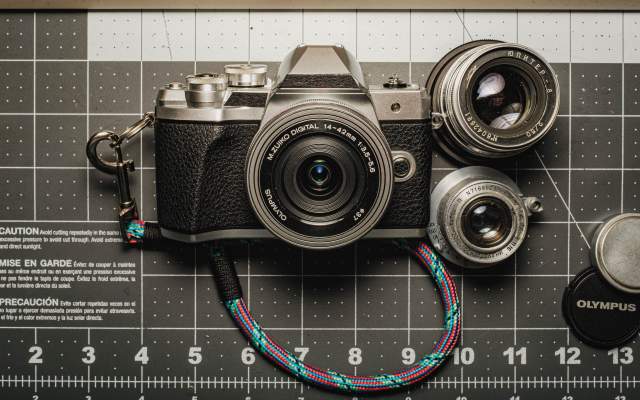 a photograph of the olympus o-md e-m10 mark iii camera, along with the vintage jupiter 8 50mm f/2.0 and industar-22 50mm f/3.5 lenses