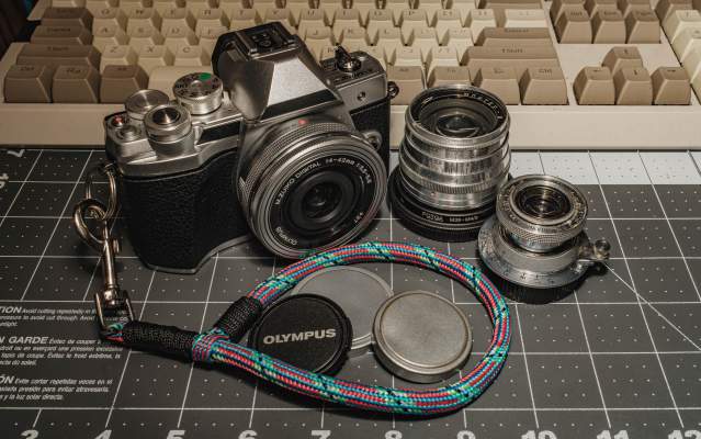a photograph of the olympus o-md e-m10 mark iii camera, along with the vintage jupiter 8 50mm f/2.0 and industar-22 50mm f/3.5 lenses